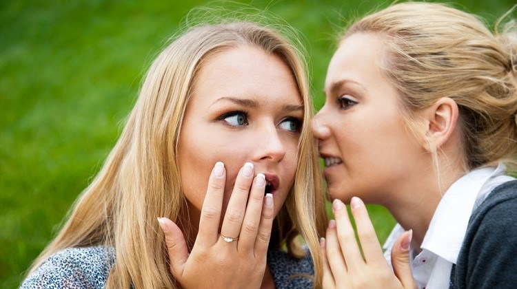 Two women whispering and smiling