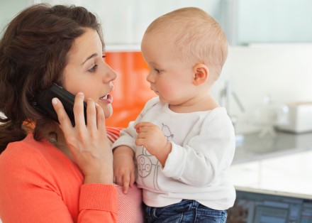 Mother holding baby and talking on cell phone