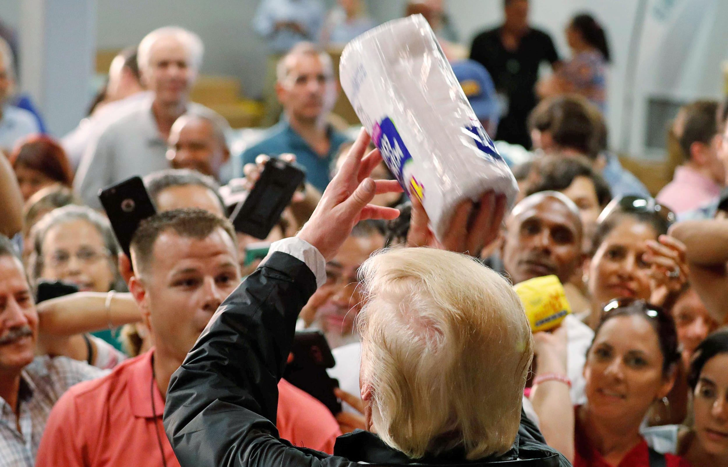 Image: President Trump throws rolls of paper towels to residents gathered in a chapel while visiting areas damaged by Hurricane Maria in San Juan, Puerto Rico